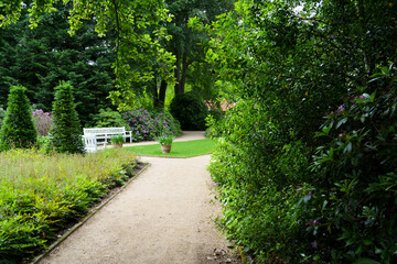 Idyllischer Sitzplatz im Park, Ort der Ruhe und Erholung, weiße Parkbank, Botanischer Garten in...