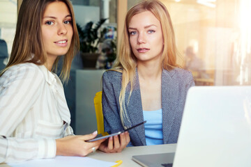 Women coworkers sitting in coworking office near computer with mock up screen