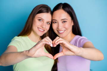 Closeup photo of affection lesbians couple ladies together make arms fingers heart shape figure happy lovers celebrate anniversary wear casual t-shirts isolated blue color background