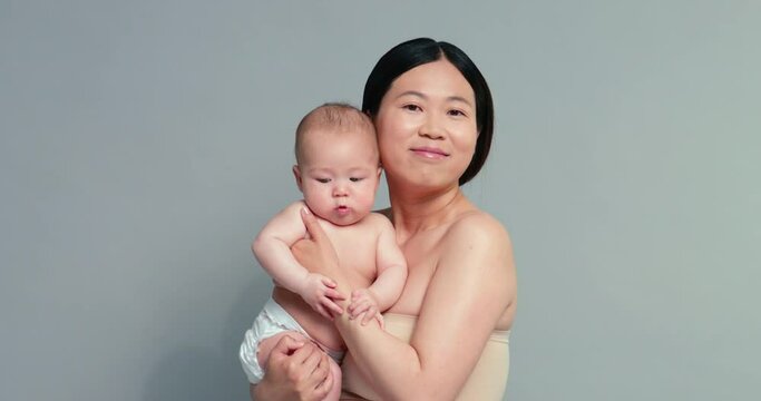 SLO MO MS Studio portrait of woman holding baby son (6-11 months)