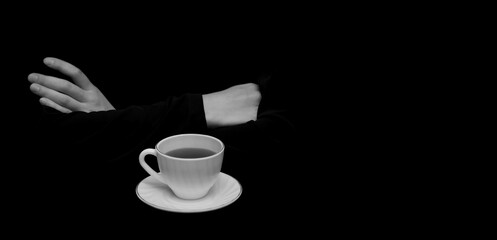 White female hands, folded in a waiting gesture, next to a white tea pair. Selective focus, black isolated background, low key. Close-up, image layout, place to copy text, banner.