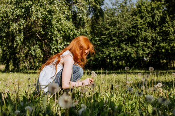 Red-haired girl collects flowers in a clearing