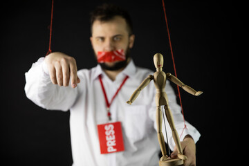 Man with badge press holds hands tied with ropes like marionette with wrapping mouth by adhesive...