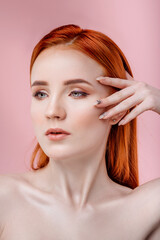 Red-haired girl on a pink background. Portrait of a beautiful healthy girl with clean skin and natural makeup on a pink background. Beauty concept.