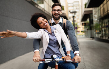 Happy business couple riding bike through city and having fun