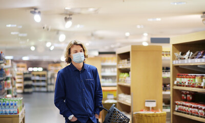 Supermarket shopping, face mask and gloves,Young man shopping in supermarket, reading product information