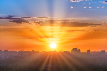 Sunset in big city, landscape with dramatic sky, clouds and sun rays