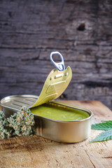 marijuana buds. medical cannabis butter in a open tin can. hemp leaves. vertical orientation.