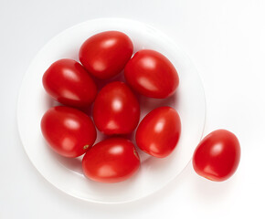fresh red tomatoes on a round plate on a white background