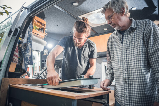 Two men installing a stove into a camper van