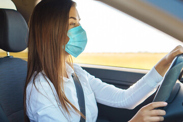 Nice business woman driving a car in a face mask.