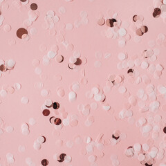 Pink celebration background with holiday sparkling confetti. Flat lay, top view