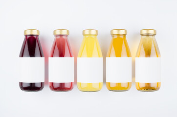 Large collection of summer fresh fruits juices in glass bottles with blank label, cap on white background, mock up for design, advertising, branding product.
