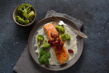 Grilled salmon with roasted red grapes and broccoli in creamy garlic sauce. Tuscan sea food recipe. Italian  gourmet cuisine. Healthy food concept. Omega -3, Keto diet
