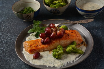 Grilled salmon with roasted red grapes and broccoli in creamy garlic sauce. Tuscan sea food recipe. Italian  gourmet cuisine. Healthy food concept. Omega -3, Keto diet