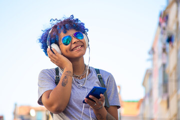 urban young girl with smartphone and headphones listening to music outdoors in the city