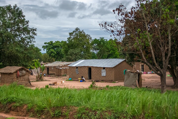 View of traditional village, people and animals, thatched and zinc sheet on roof houses and...