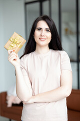 Portrait of happy smiling woman holding golden gift box. Celebrating concept.