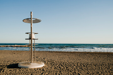 Lifeguard tower on the beach, with surfer in the water, blue sky