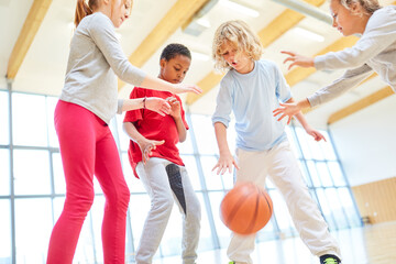 Kinder spielen Basketball im Sportunterricht