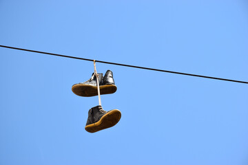 Flying sneakers - pair of old black sneakers hanging on wire - Powered by Adobe
