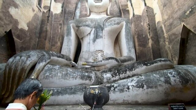 A Thai man prays in front of Big Buddha at Wat Sri Chum, Sukhothai, Thailand