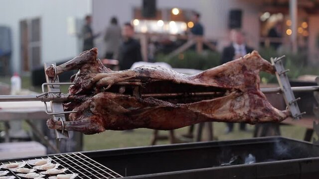 Suckling pig roasting on a rotisserie spit, medium close up