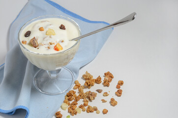 Yogurt in a beautiful glass bowl next to a box of granola and a spoon.