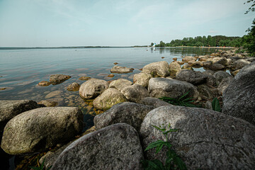 a pile of large stones on the shore of a beautiful lake