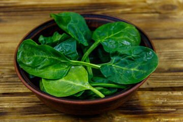 Fresh green spinach leaves in bowl on a wooden table