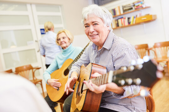 Smiling senior woman takes guitar lessons
