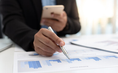 Naklejka premium Financial businessmen use mobile phones to calculate income and analyze data about the company's financial performance to prepare for presentation to customers, Tax and accounting system concept.