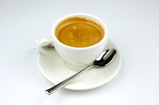 coffee on a white plate with a spoon on a white background