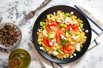 Obraz na płótnie Canvas Fresh bulgur salad with tomatoes, avocado and feta cheese. Vegetarian salad with bulgur