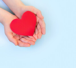 Obraz na płótnie Canvas Children's hands hold red heart on a light background. Сoncept health care, organ donation, wellbeing, family insurance,love.World health day.National Organ Donor Day.World heart day.
