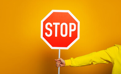 Stop sign. Girl in a yellow hoodie showing only her hand with "stop" sign.