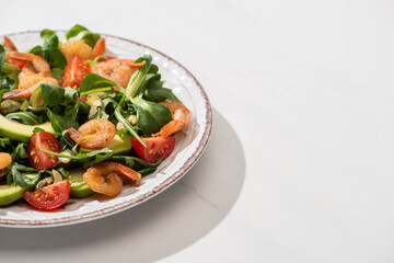 fresh green salad with shrimps and avocado on plate on white background
