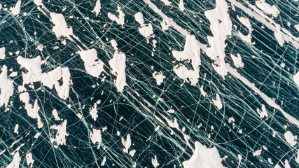 Frozen Lake Baikal, Aerial view. Beautiful winter landscape with clear smooth ice. Famous natural landmark Russia. Blue transparent ice with deep cracks, top view of a frozen lake.