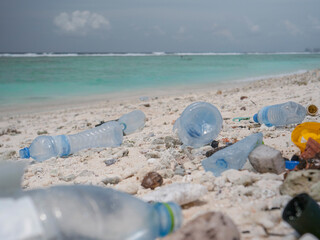 Fototapeta na wymiar CLOSE UP: Plastic canisters and bottles are scattered around the tropical shore.