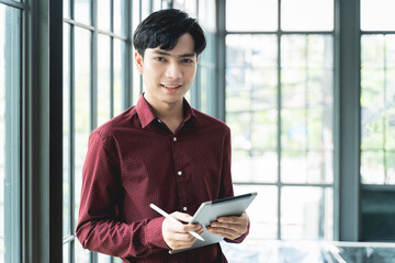 Men are smiling and cheerful. Using the tablet and holding it on hand. He use tablet to work, check emails, teleconferences, or social networks. During work from home at the Home Office.