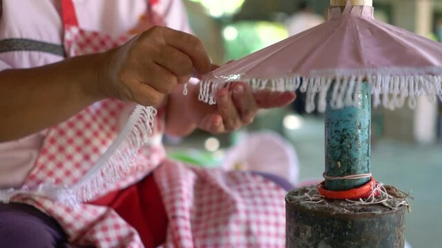 A Thai Woman Attaching White Truffles To A Small Pink Umbrella As Embellishment In Chiang Mai, Thailand - close up
