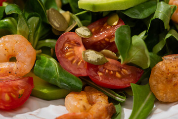 close up view of fresh green salad with pumpkin seeds, cherry tomatoes, shrimps and avocado