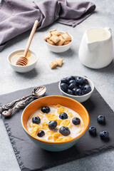 Corn flakes made from natural cereals with fresh blueberries, honey and milk. The concept of a healthy wholesome Breakfast. copy space Grey concrete background
