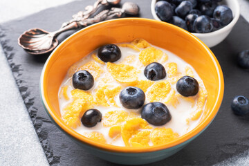 Corn flakes made from natural cereals with fresh blueberries, honey and milk. The concept of a healthy wholesome Breakfast. copy space Grey concrete background