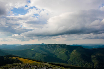 Beautiful view of the mountains from above, the rays of the sun make its way through the clouds, bright sky, evening