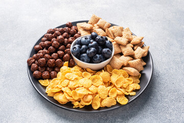 Set of dry cereal flakes for Breakfast with milk and berries. Healthy natural food. copy space Grey concrete background