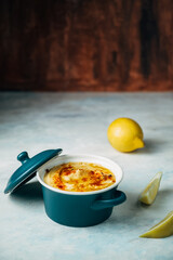 Front view of a plate of hummus with olive oil and paprika. next to it there is lemon. it is on a white wooden background Food concept
