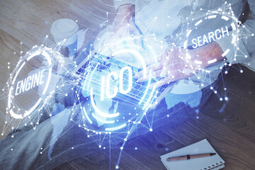 Crypto currency theme hologram with businessman working on computer on background. Concept of blockchain. Double exposure.