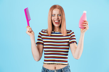 Image of joyful charming girl holding shampoo and comb while laughing