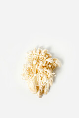 Heap of little white enoki mushrooms on neutral white background, close-up